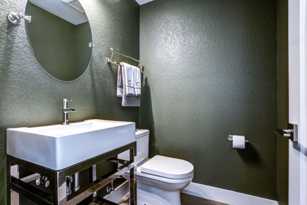 small powder room green wall round mirror
